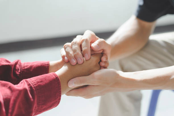 Close-up of man psychologist or psychiatrist sitting and holding hands palm of his woman patient for encouragement. PTSD Mental health concept,
